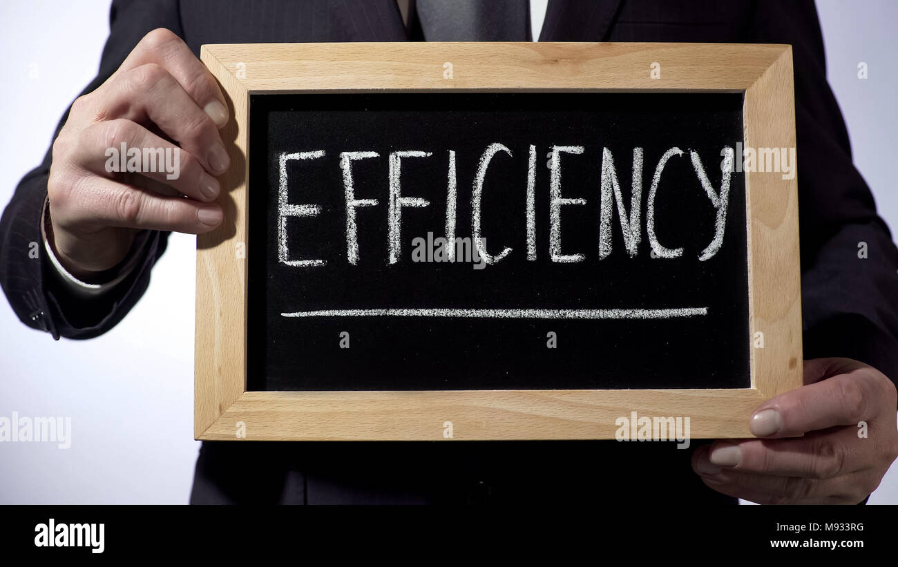 Efficiency written on blackboard, male in black suit holding sign ...
