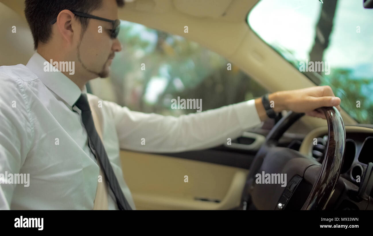 Handsome man driving expensive car to work, business class transport