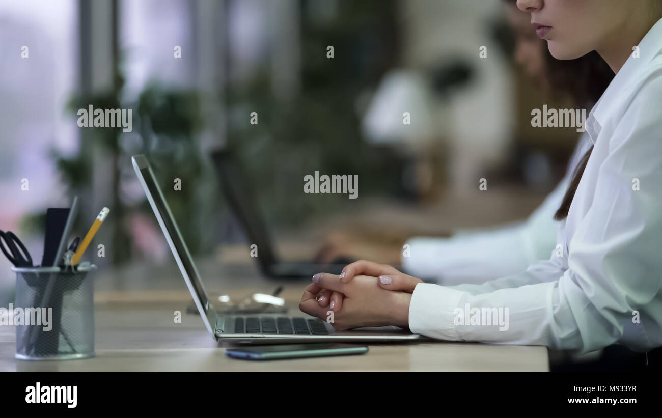 Serious female office employee sitting with hands folded, tired of