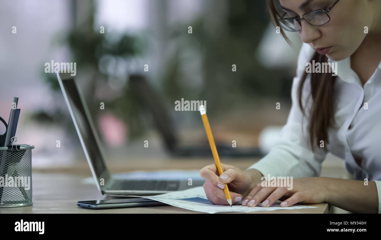 Professional financial analyst making notes on papers, woman working on report Stock Photo