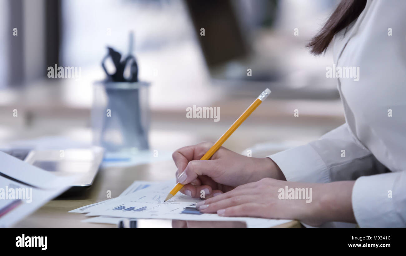 Smart female office worker busy checking documents, making notes on diagrams Stock Photo