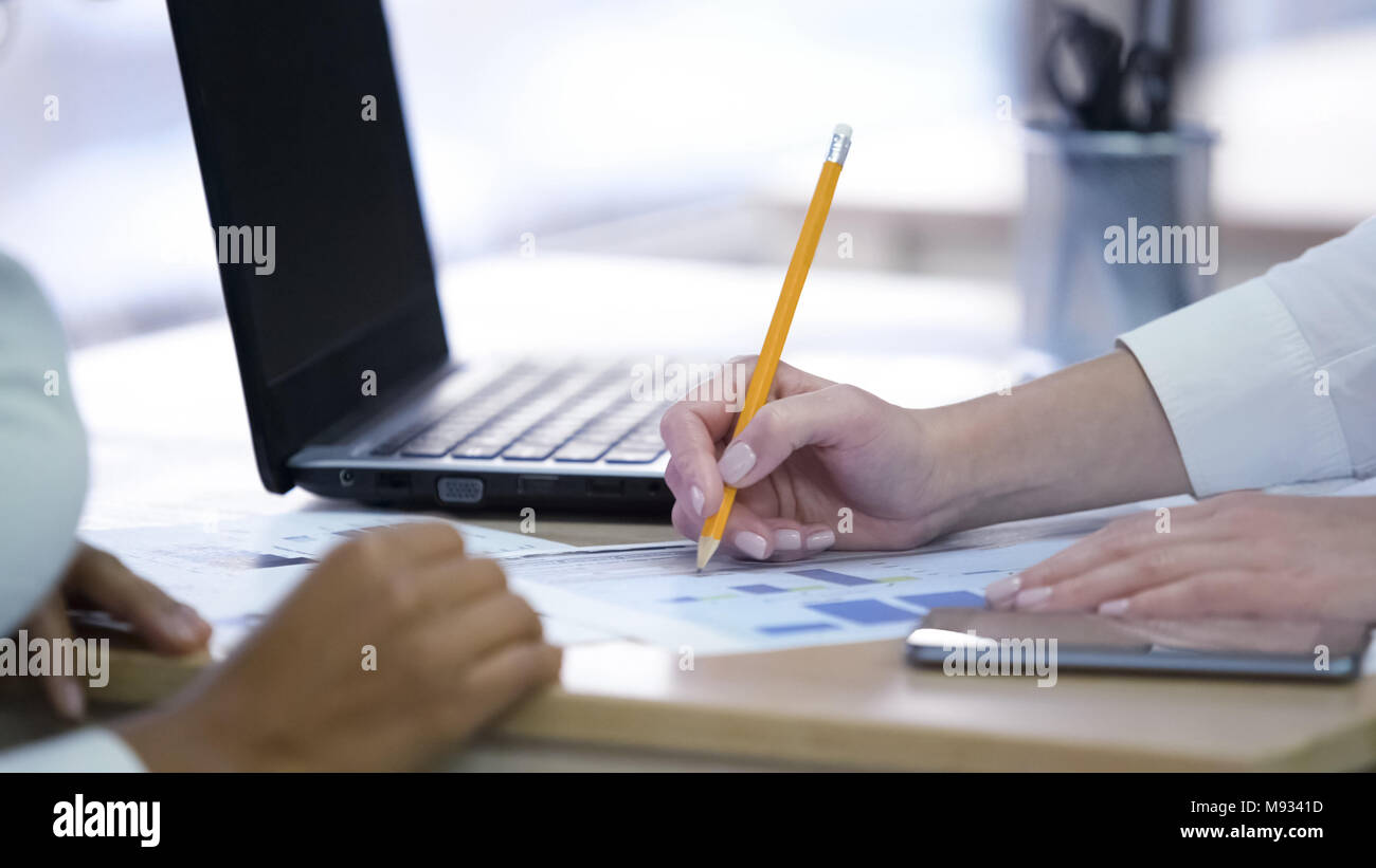 Two women making notes and discussing project, effective teamwork at office Stock Photo