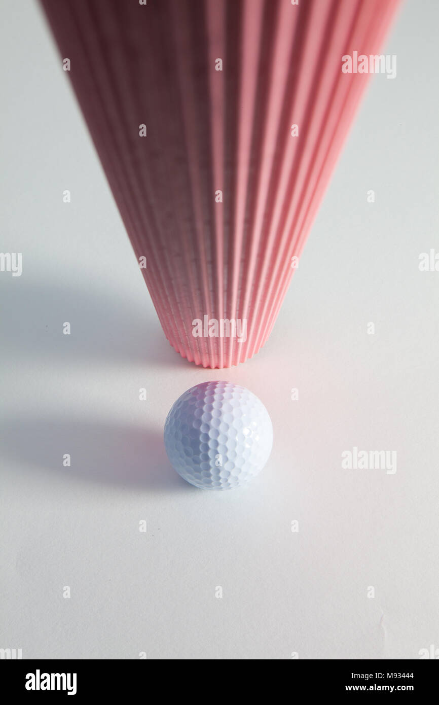Corrugated pink paper roll and golf ball on the white desk. Exclamation