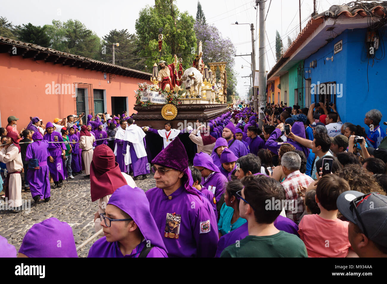 Visitors watching purple robed men carrying a float with Christ and a cross at the procession of San Bartolome de Becerra, Antigua, Guatemala Stock Photo