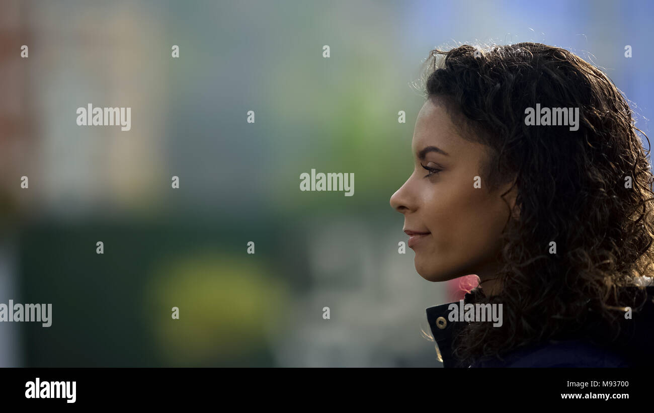 Inspired female model smiling, beautiful biracial young lady portrait in profile Stock Photo