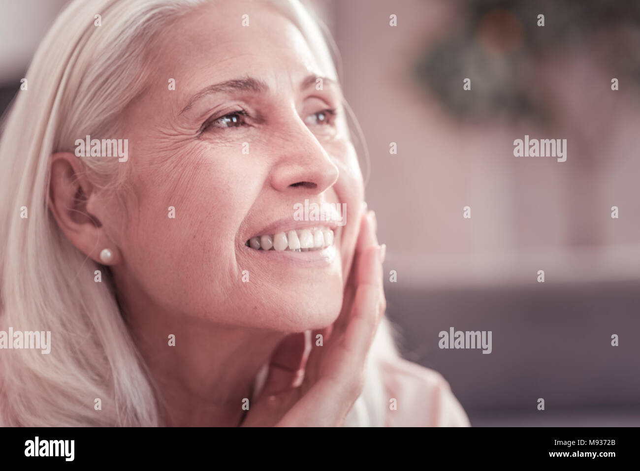 Grey haired satisfied lady looking aside and smiling. Stock Photo