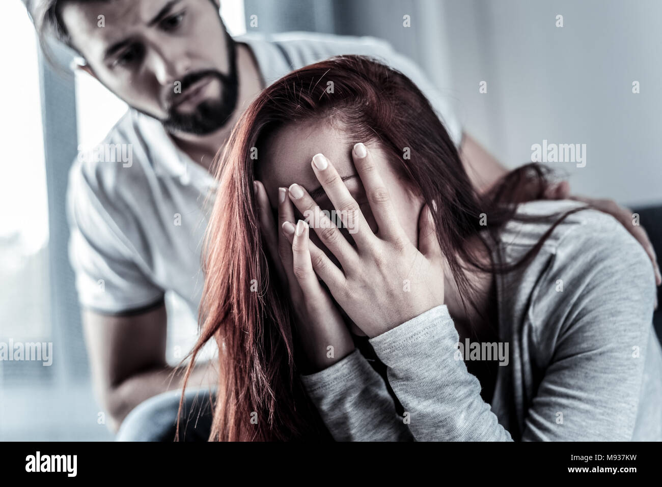 Frustrated upset woman sitting and hiding face behind hands. Stock Photo