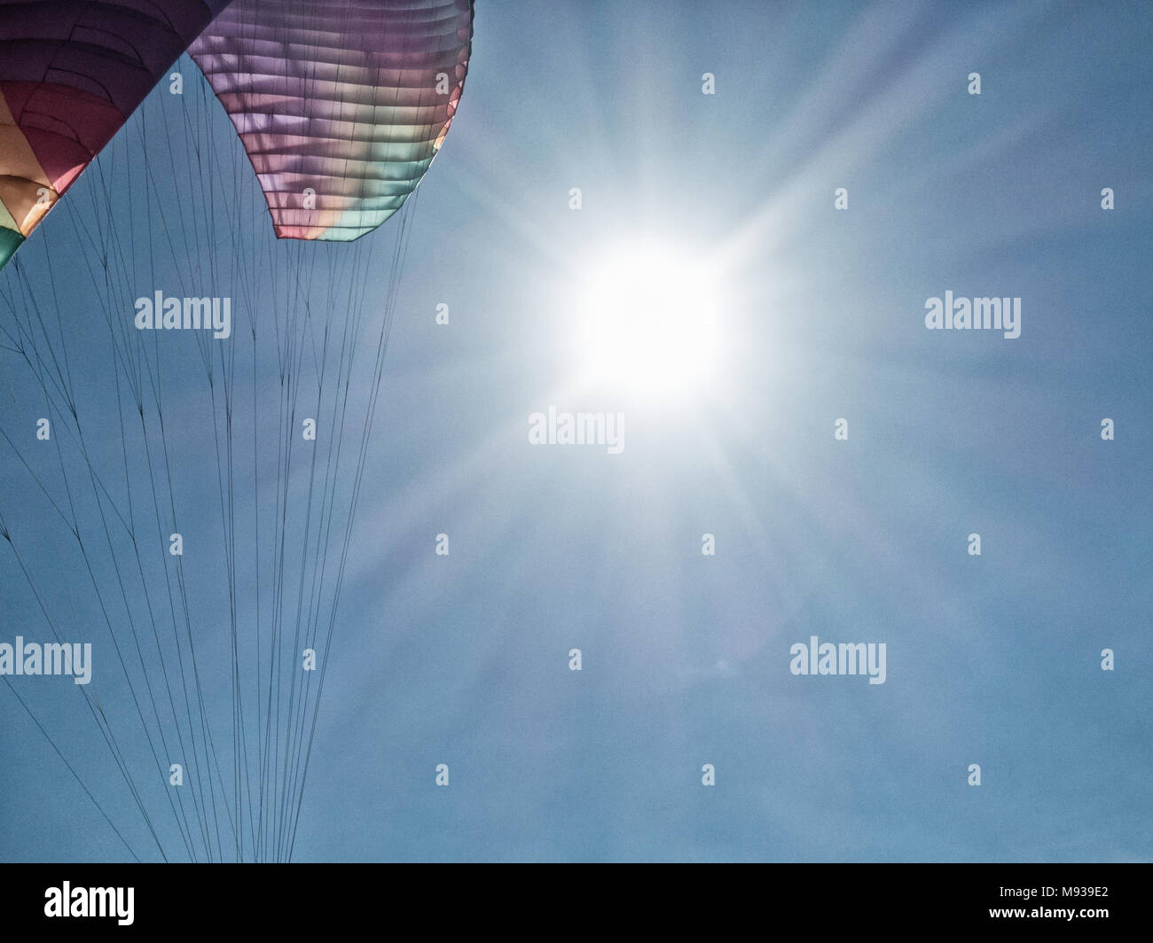 Paragliding: Paraglider with sun and blue sky in background Stock Photo
