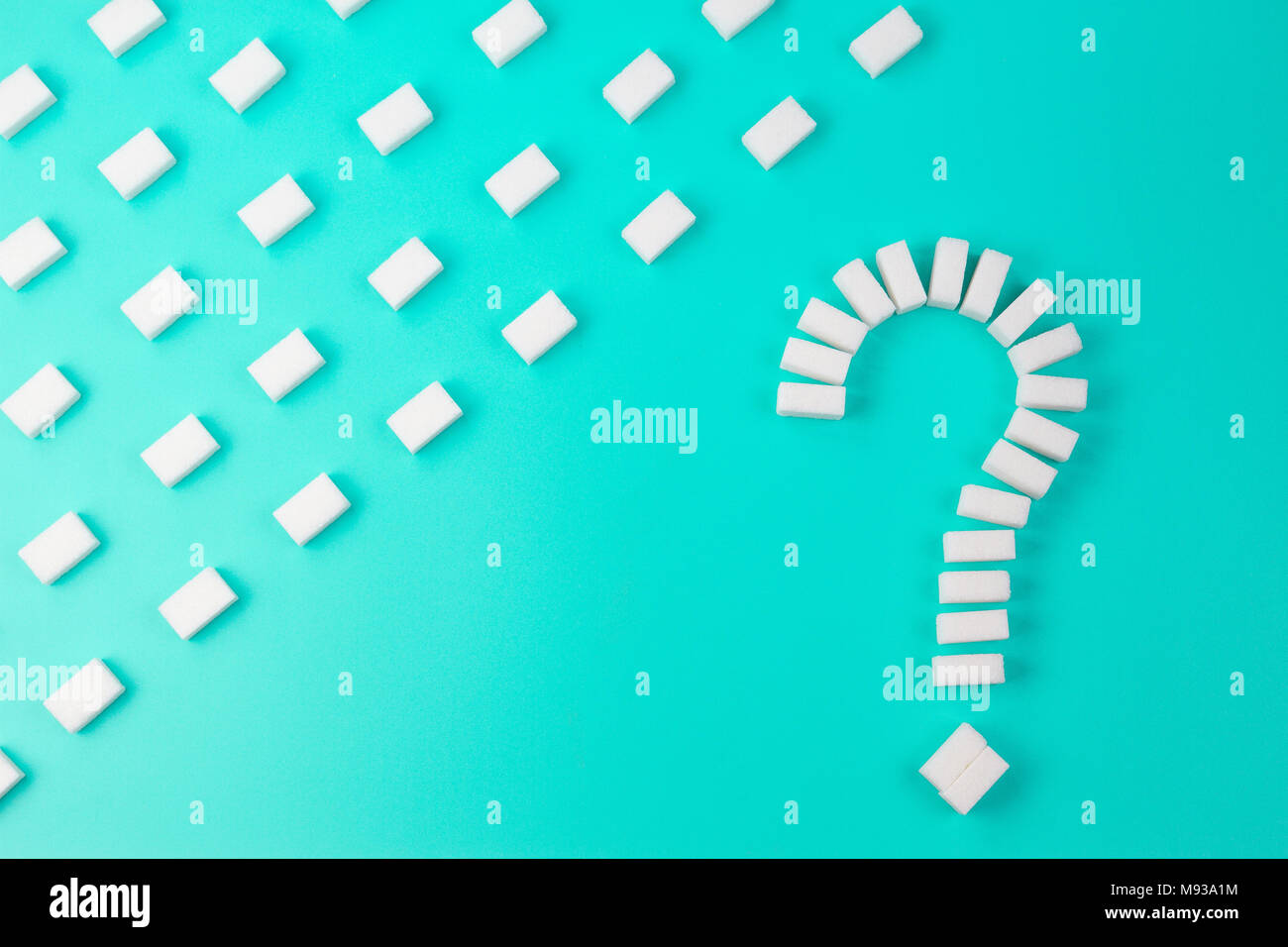 Sugar cubes shaped as a question mark sign on turquoise background. Stock Photo