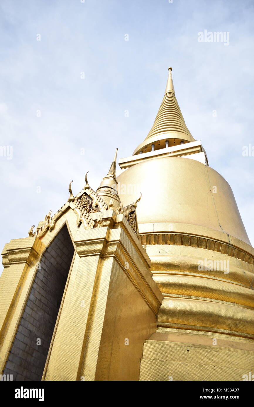 Golden chedis monument of the big palace in thailand with its gold cover and a blue sky, in the touristic area of Bangkok, Thailand. Stock Photo