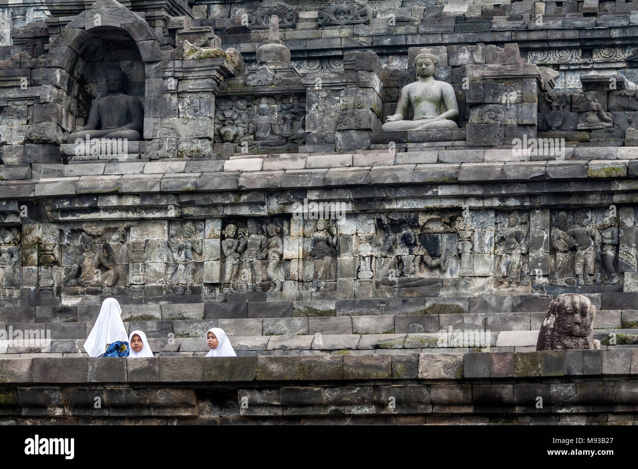Borobudur Buddhist Temple and three young Muslim girls wearing traditional Islamic headwear known as a Hijab dwarfed by the Unesco World Heritage Site Stock Photo