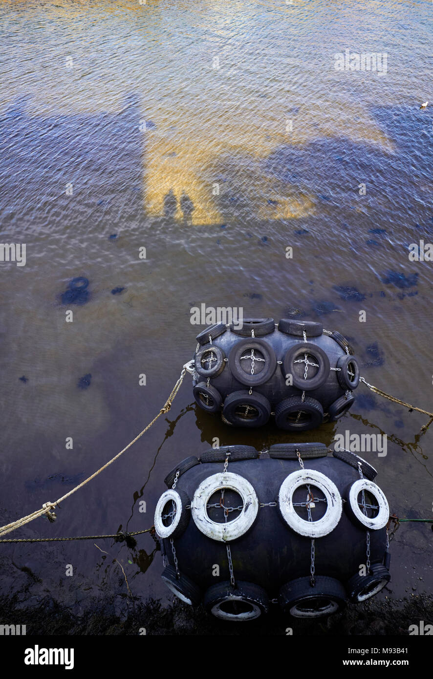 Two harbour fenders with shadows of people projected onto the water Stock Photo