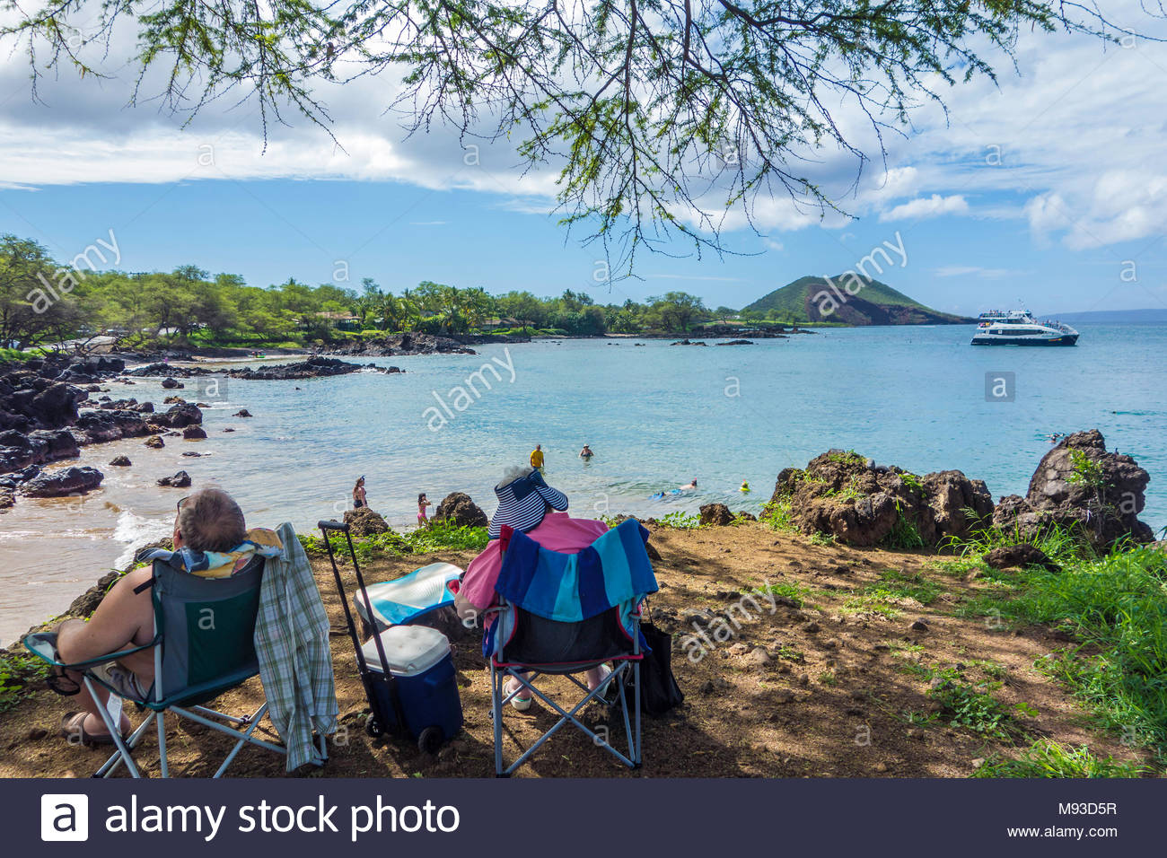 Retired couple relaxing in the shade at Makena Landing Beach Park on the island of Maui in the state of Hawaii USA Stock Photo