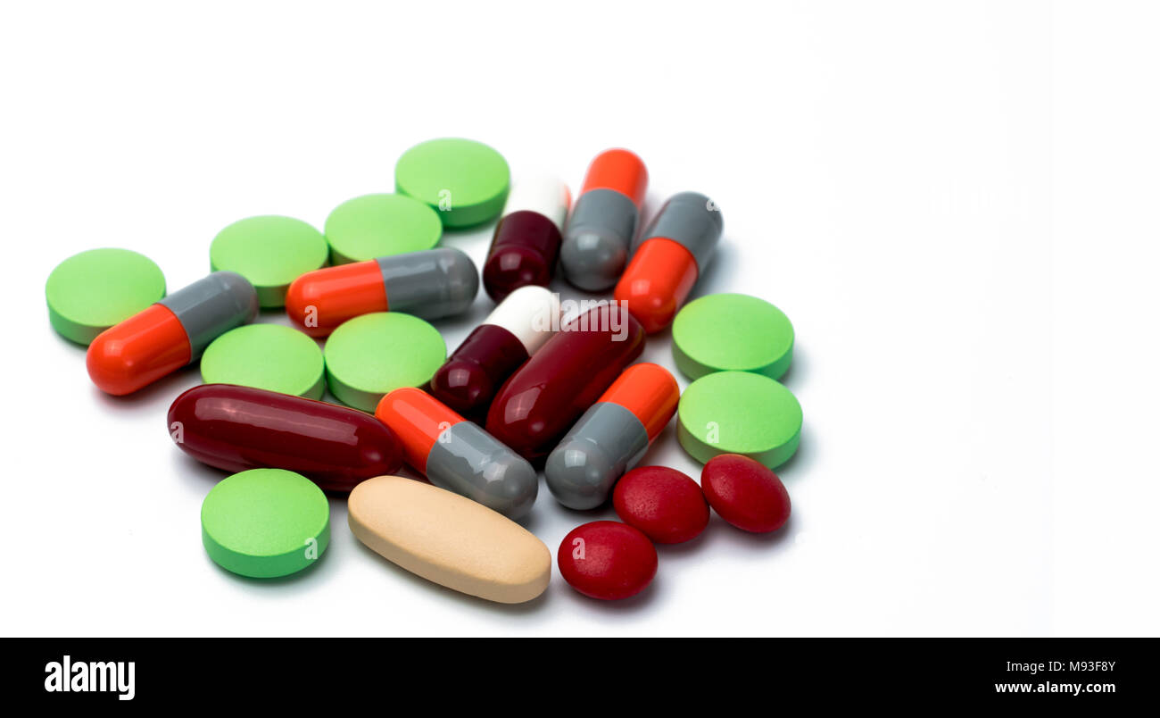 Pile of colorful tablets and capsule pills isolated on white background