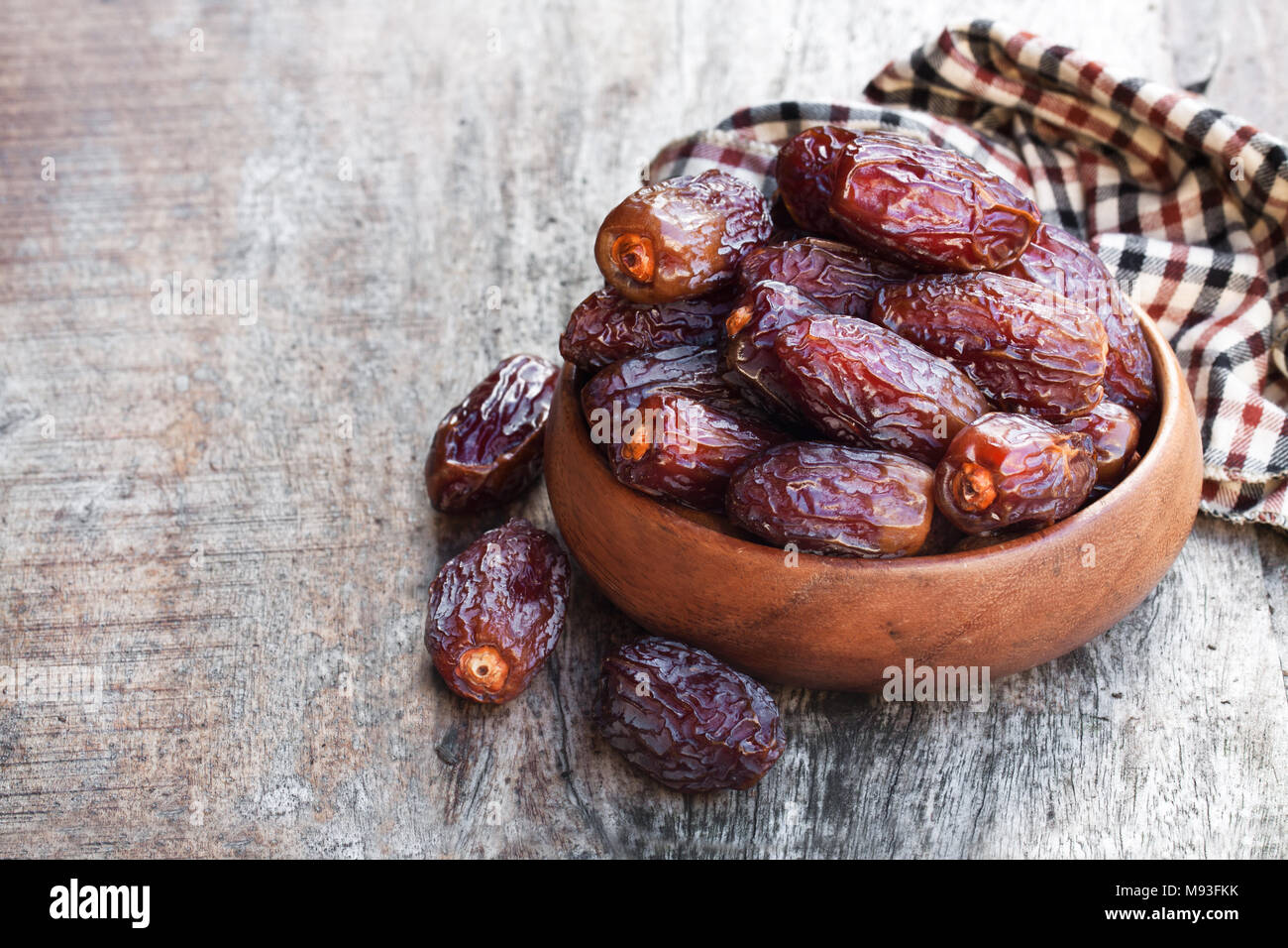 Dried dates in wooden bowl on rustic table Stock Photo - Alamy