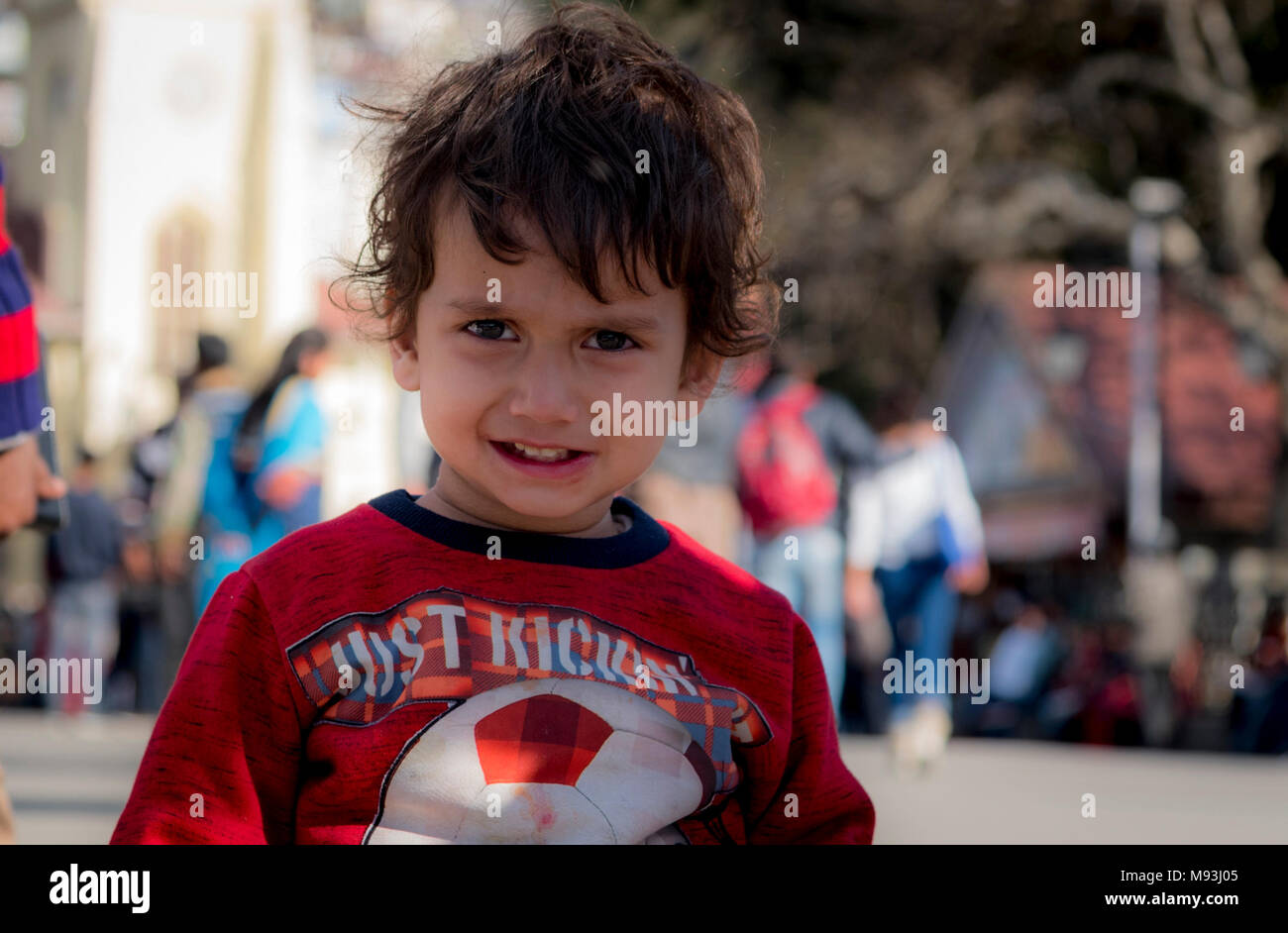 cute smiling kid face expression with fair complexion wearing red dress and head cover by winter cap. Stock Photo