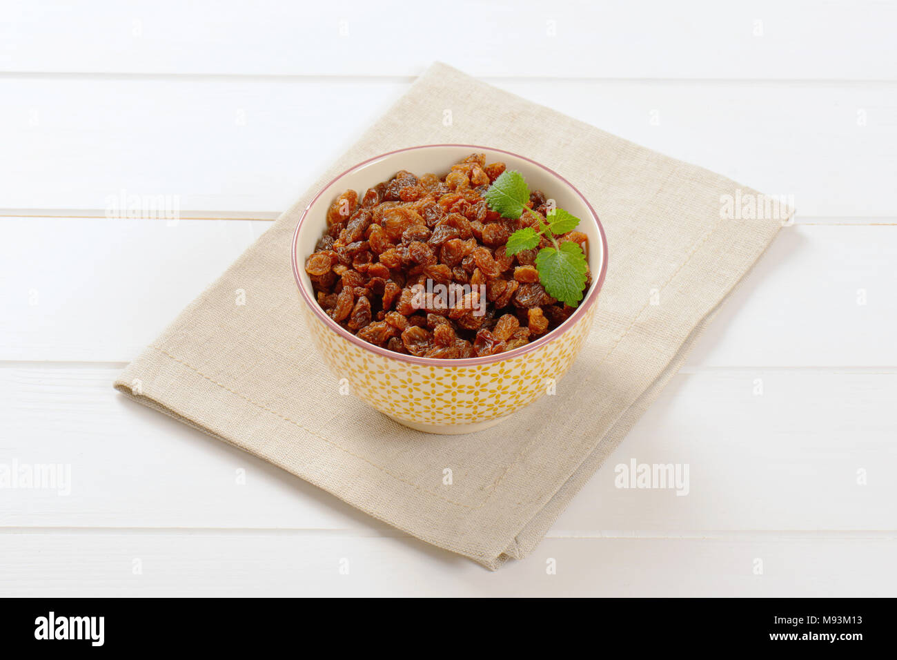 bowl of sweet raisins on beige place mat Stock Photo