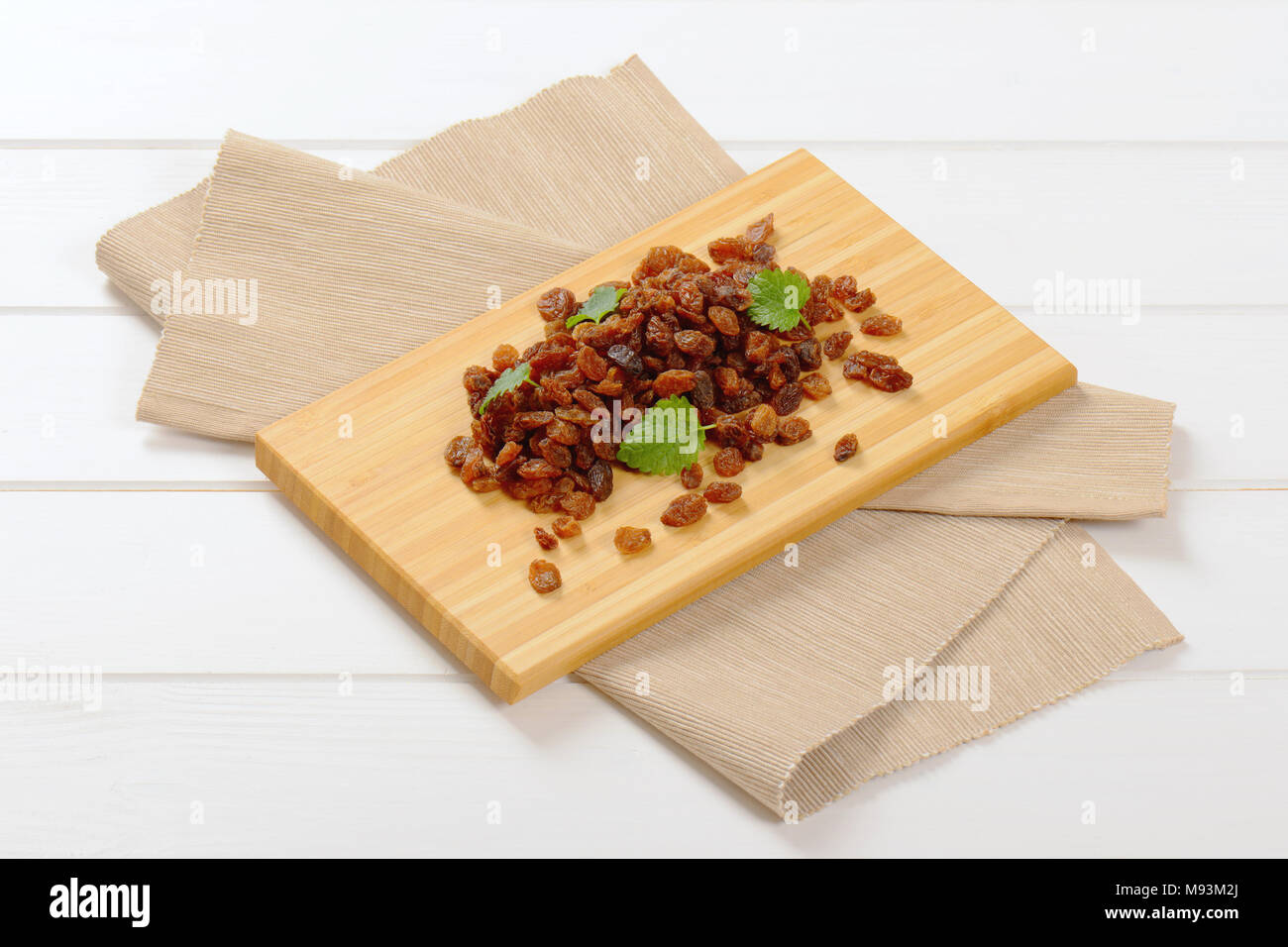 pile of sweet raisins on wooden cutting board Stock Photo