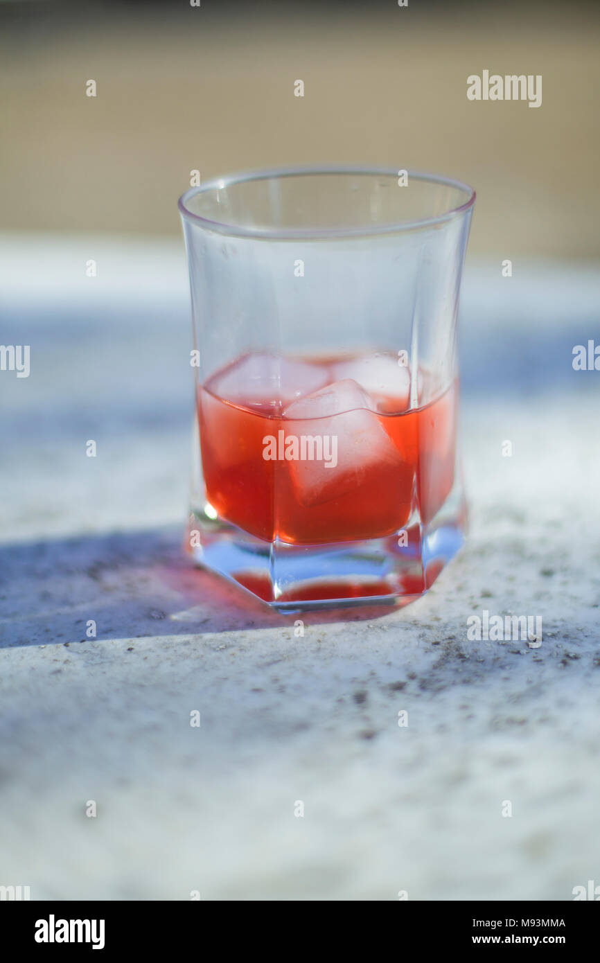 A glass of campari on a table in the sun Stock Photo