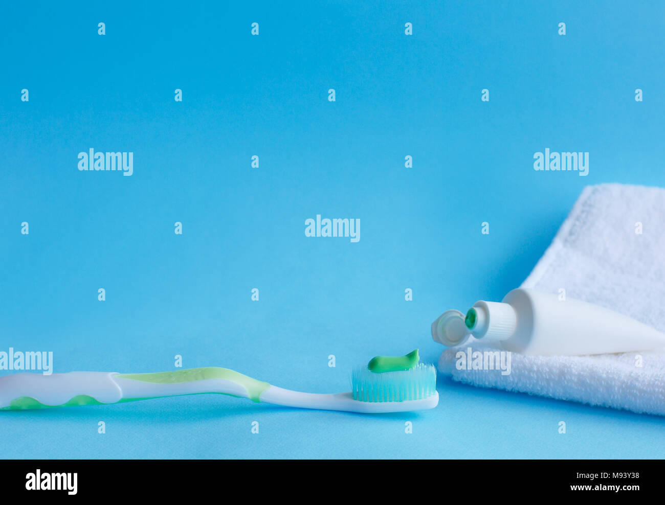 Toothbrush with toothpaste next to toothpaste that lies on a white