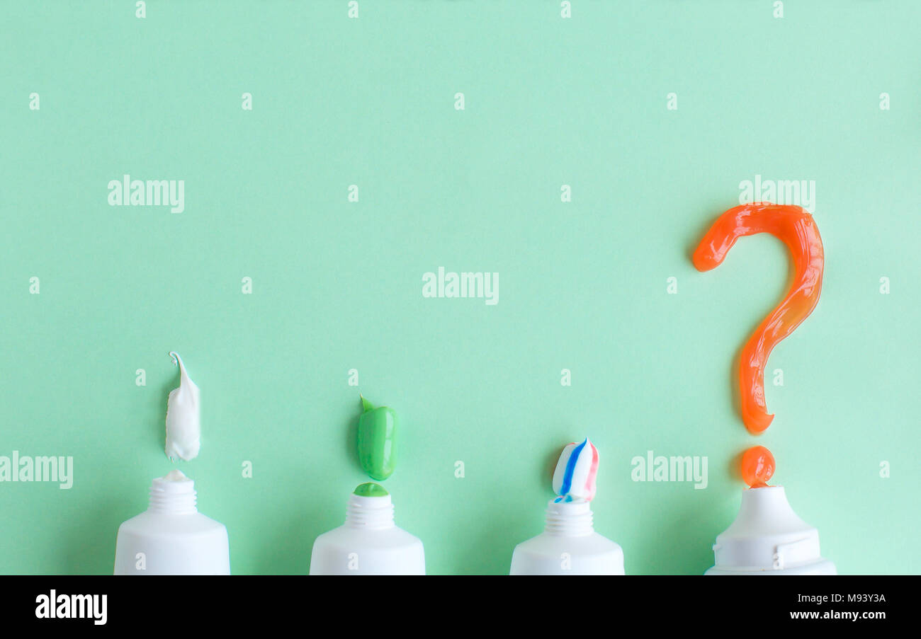 Toothpaste lies on a green background and a question mark. Choice of