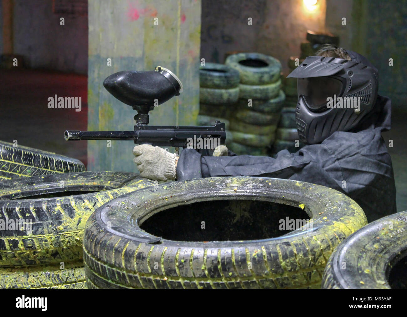 A man with a marker for paintball in the woods sitting for tires in the