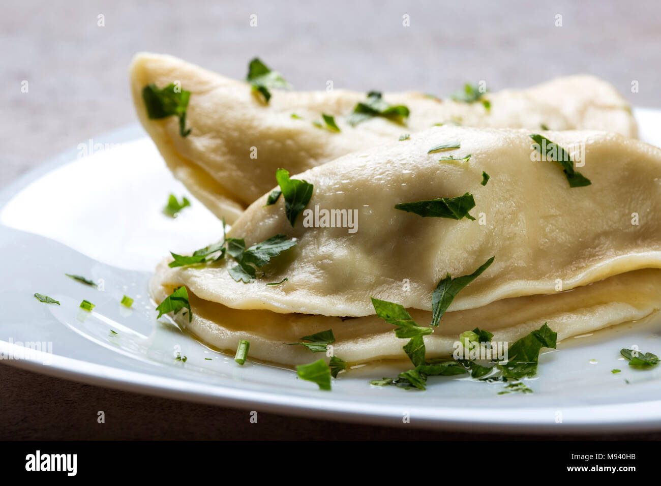Pierogi, pyrohy or dumplings, filled with beef meat and covered with parsley that can be served with sour cream Stock Photo