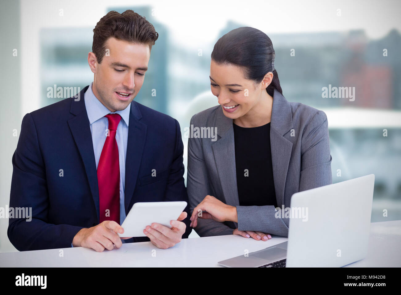 Composite image of executives discussing over tablet while sitting against white background Stock Photo