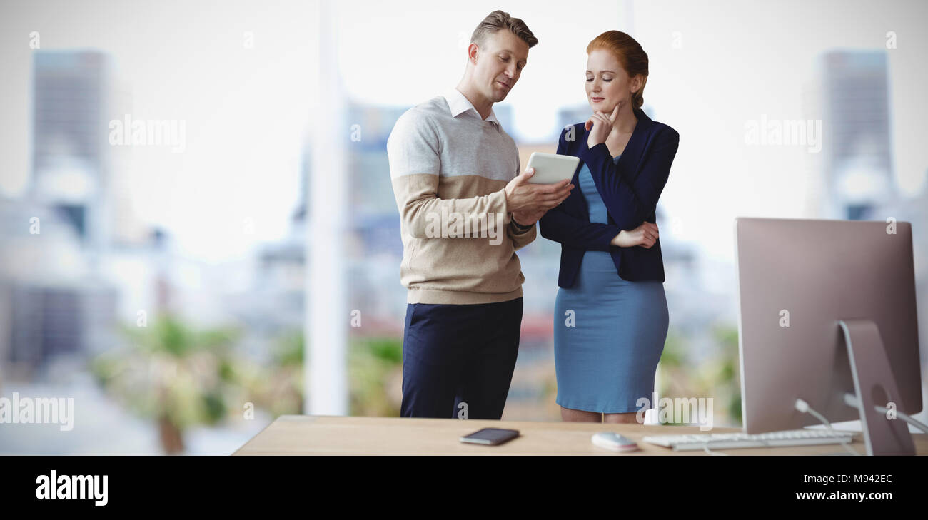 Composite image of colleagues discussing over tablet while standing at table Stock Photo