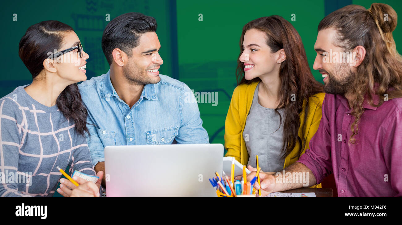 Composite image of colleagues discussing over laptop while sitting at desk Stock Photo