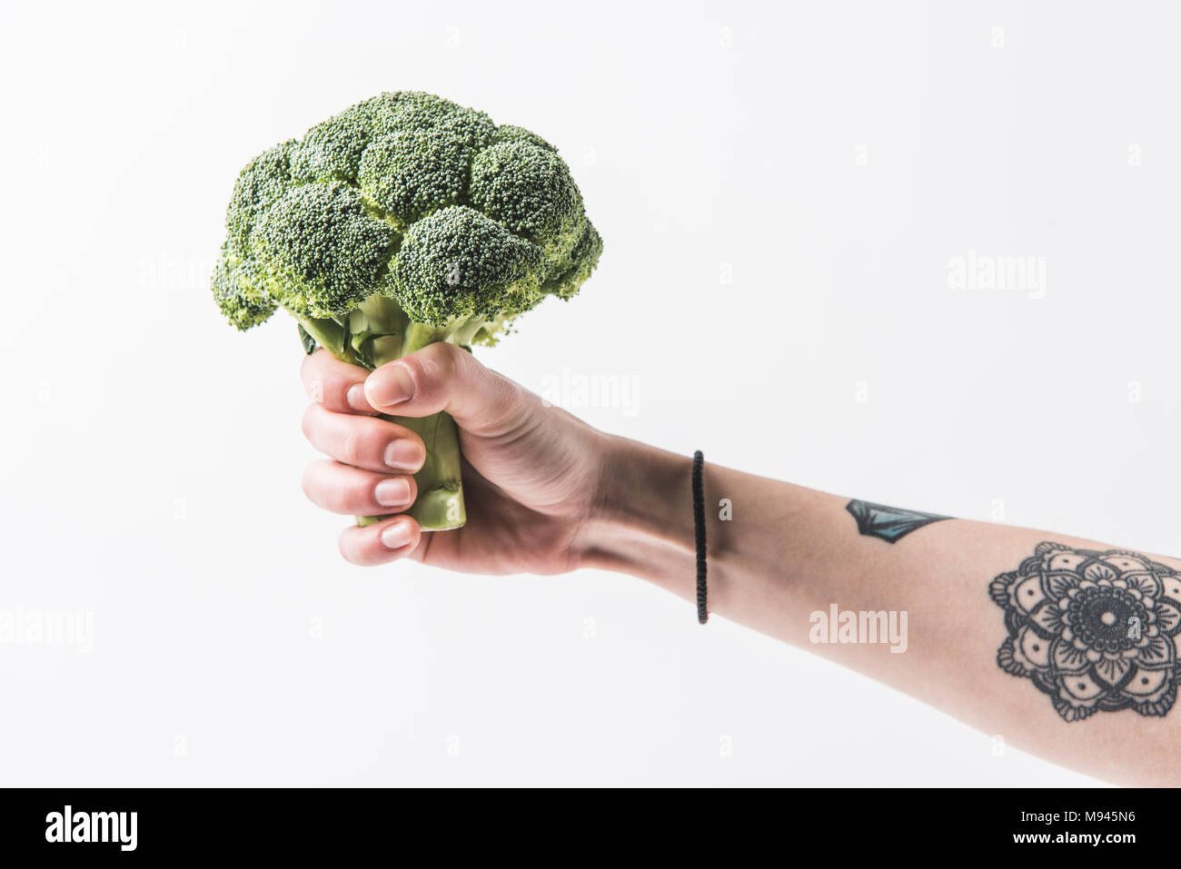 Hand holding raw broccoli cabbage florets isolated on white background Stock Photo