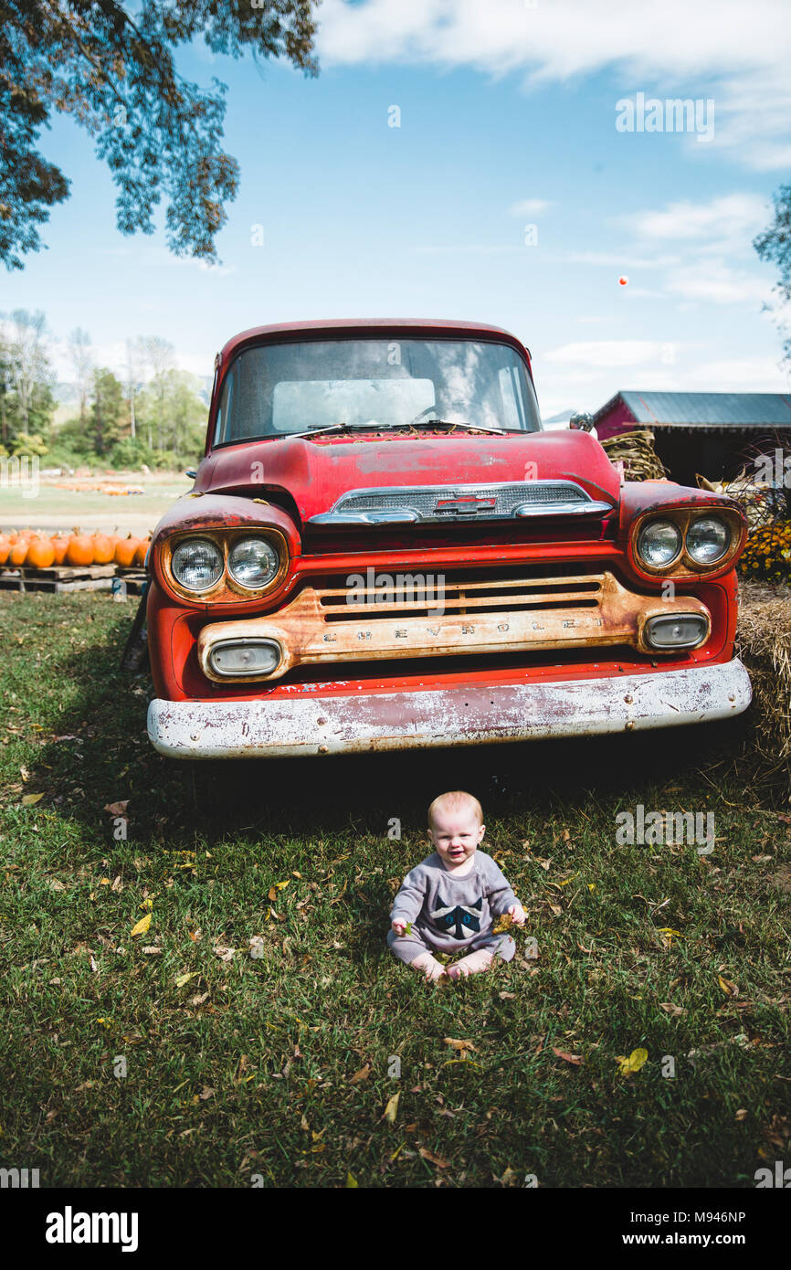 Baby sitting in front of red truck Stock Photo