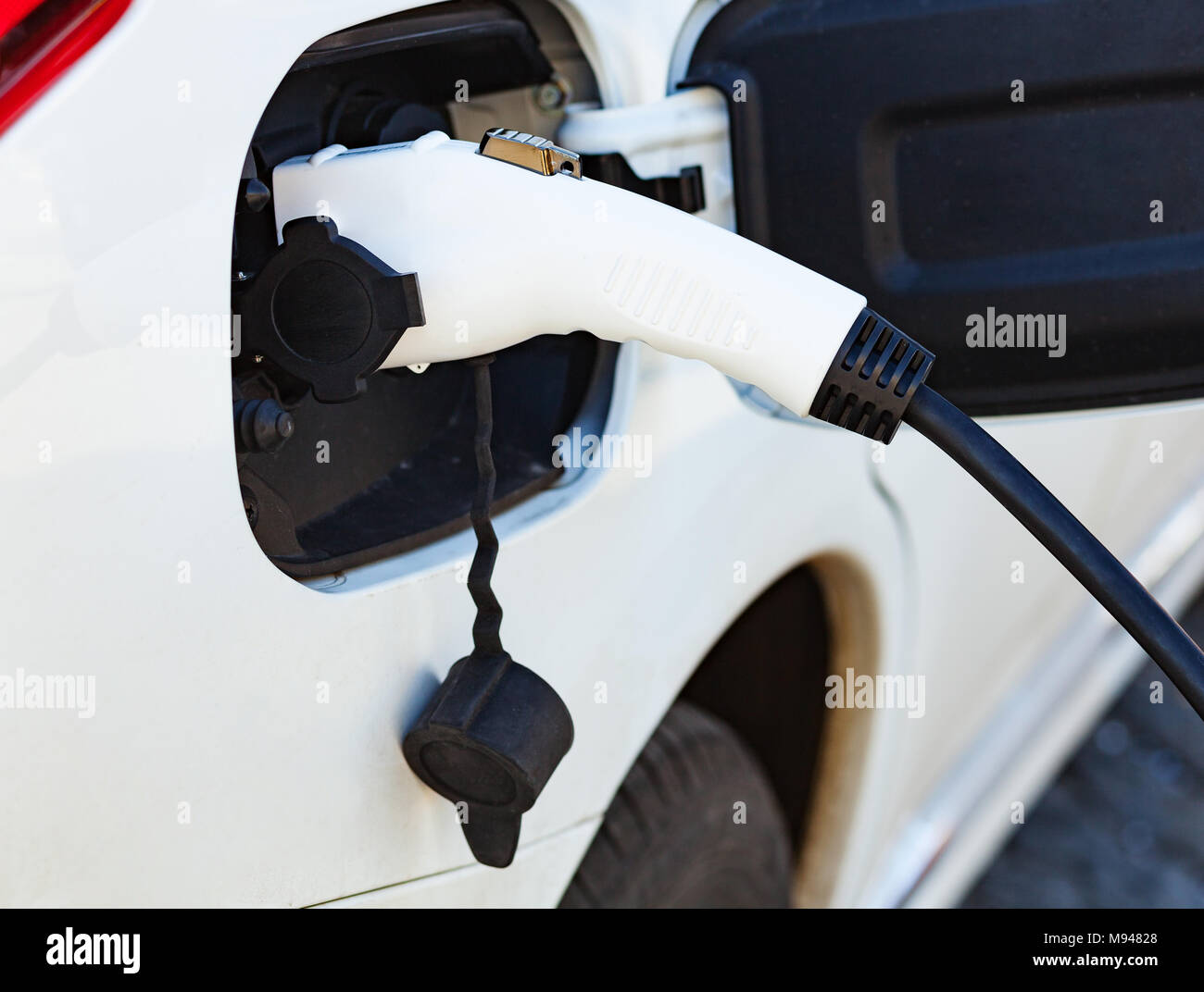 The electric car charger plugged in to the socket.The modern electric car charging the battery. Stock Photo