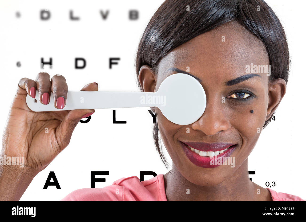 Young African lady taking an eyesight test examination at an optician clinic whith Eye Chart Illustrations on background Stock Photo