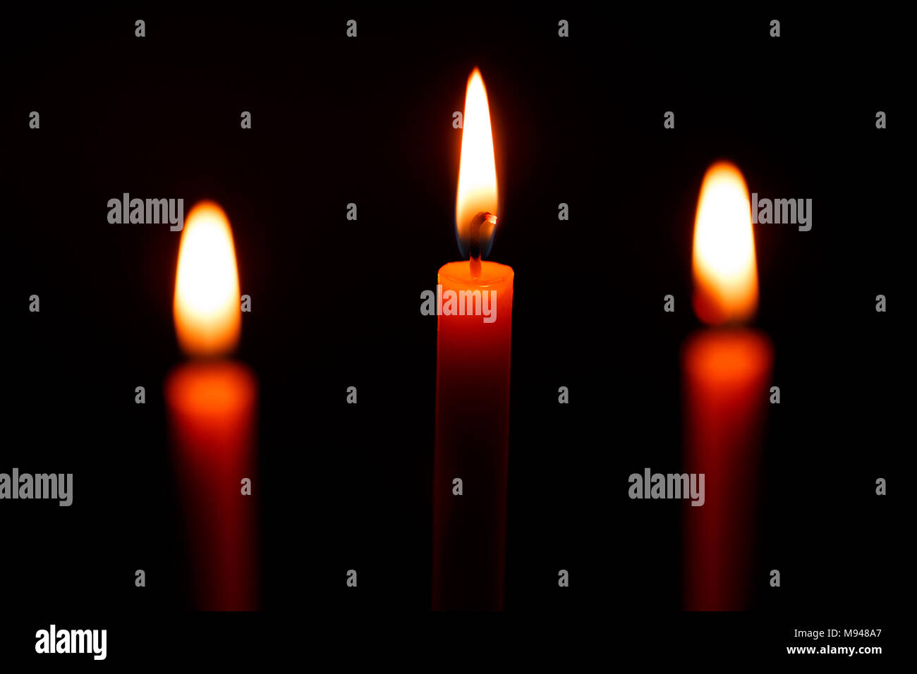 Three candles on black background Stock Photo - Alamy