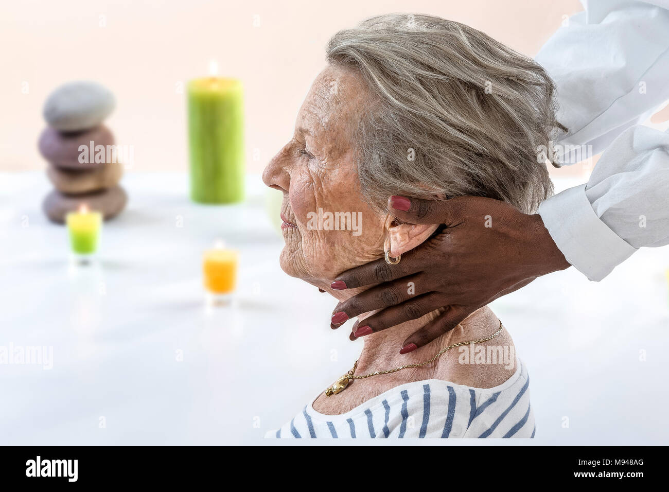 people, beauty, spa, healthy lifestyle and relaxation concept - close up of old woman sitting proile view with closed eyes and having massage in spa Stock Photo