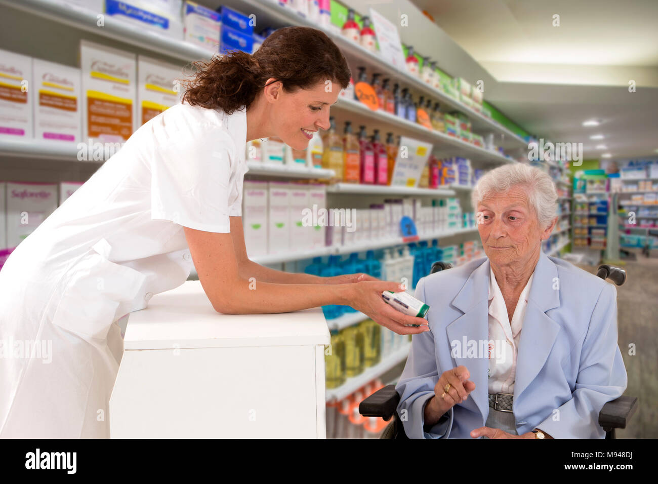 female pharmacist taking prescription from disabled woman wheelchair in