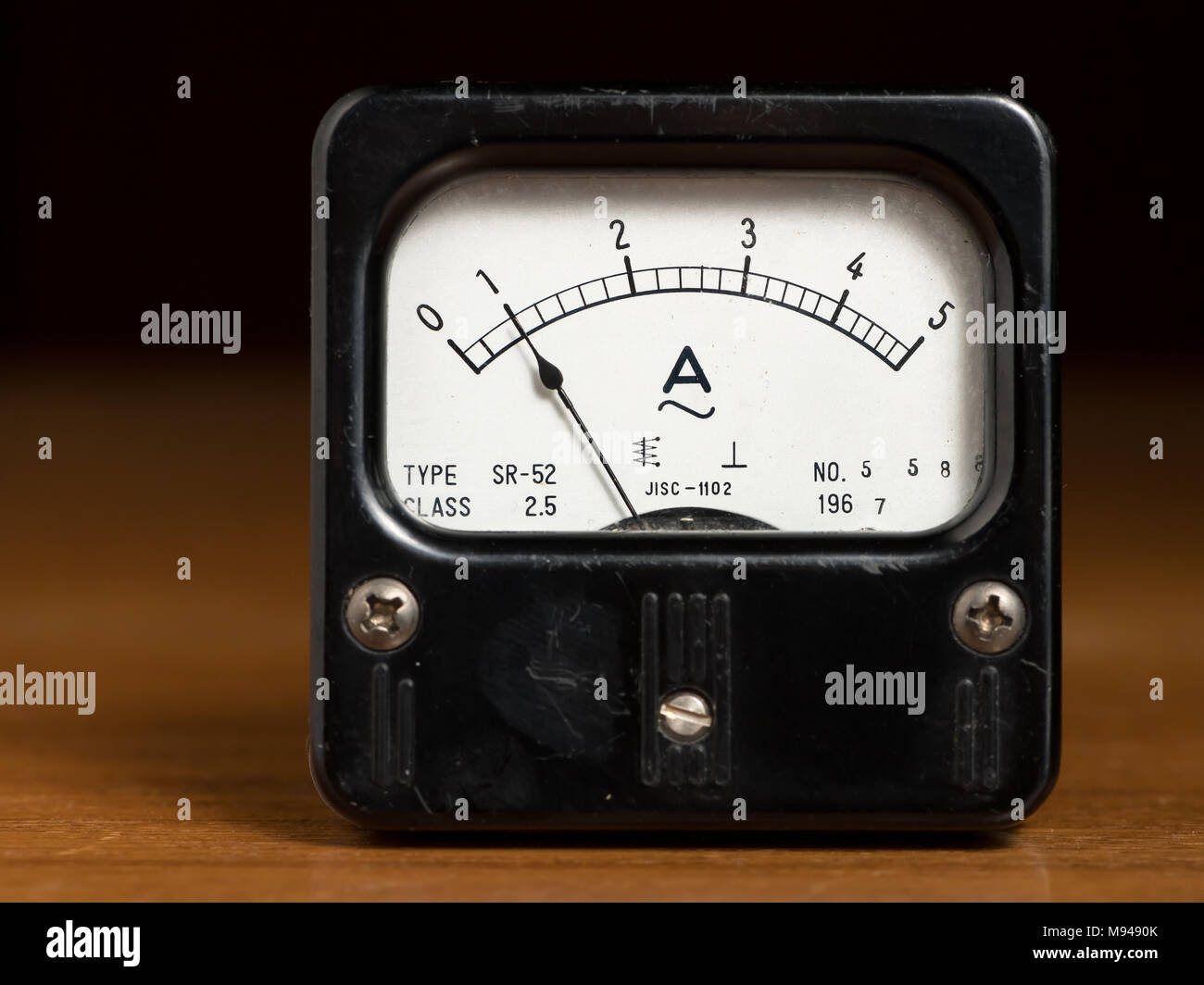Closeup of an old black analog ampere meter on a wooden table Stock Photo
