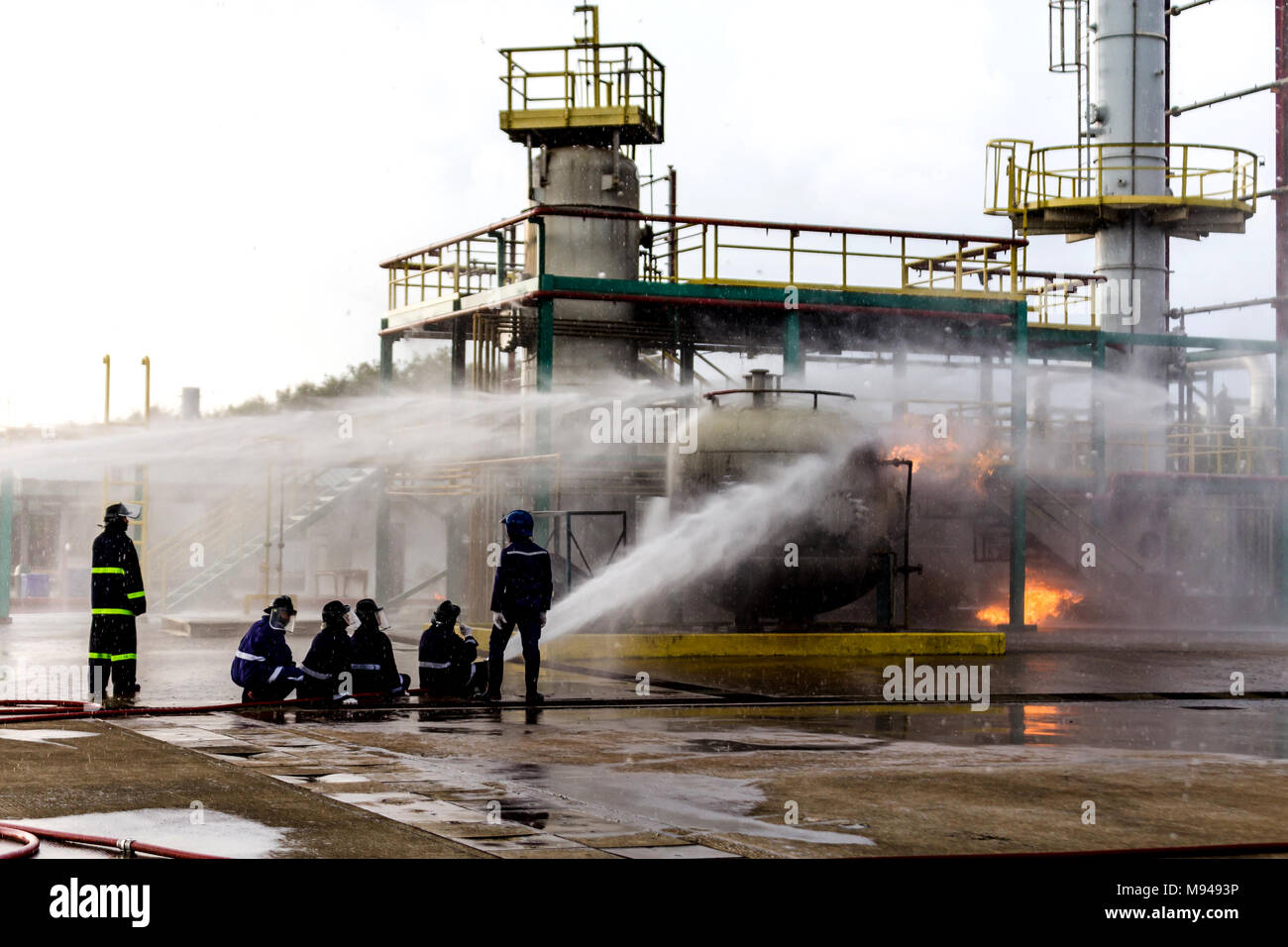 Firemen using water from hose for fire fighting at firefight training ...