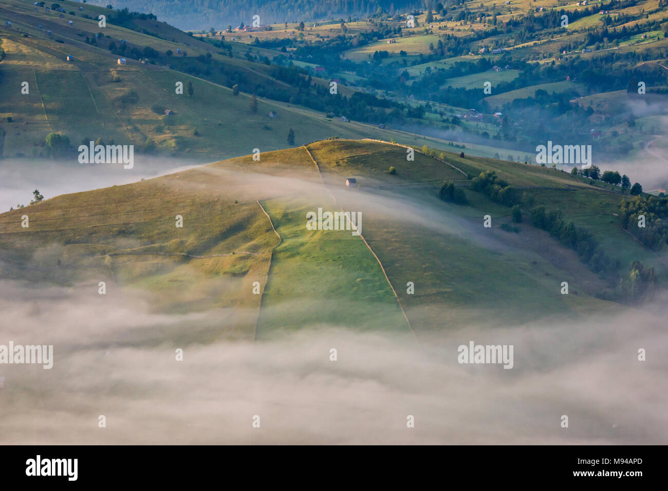 Sunrise over the misty rolling hills of the Romanian countryside in Bucovina region Stock Photo