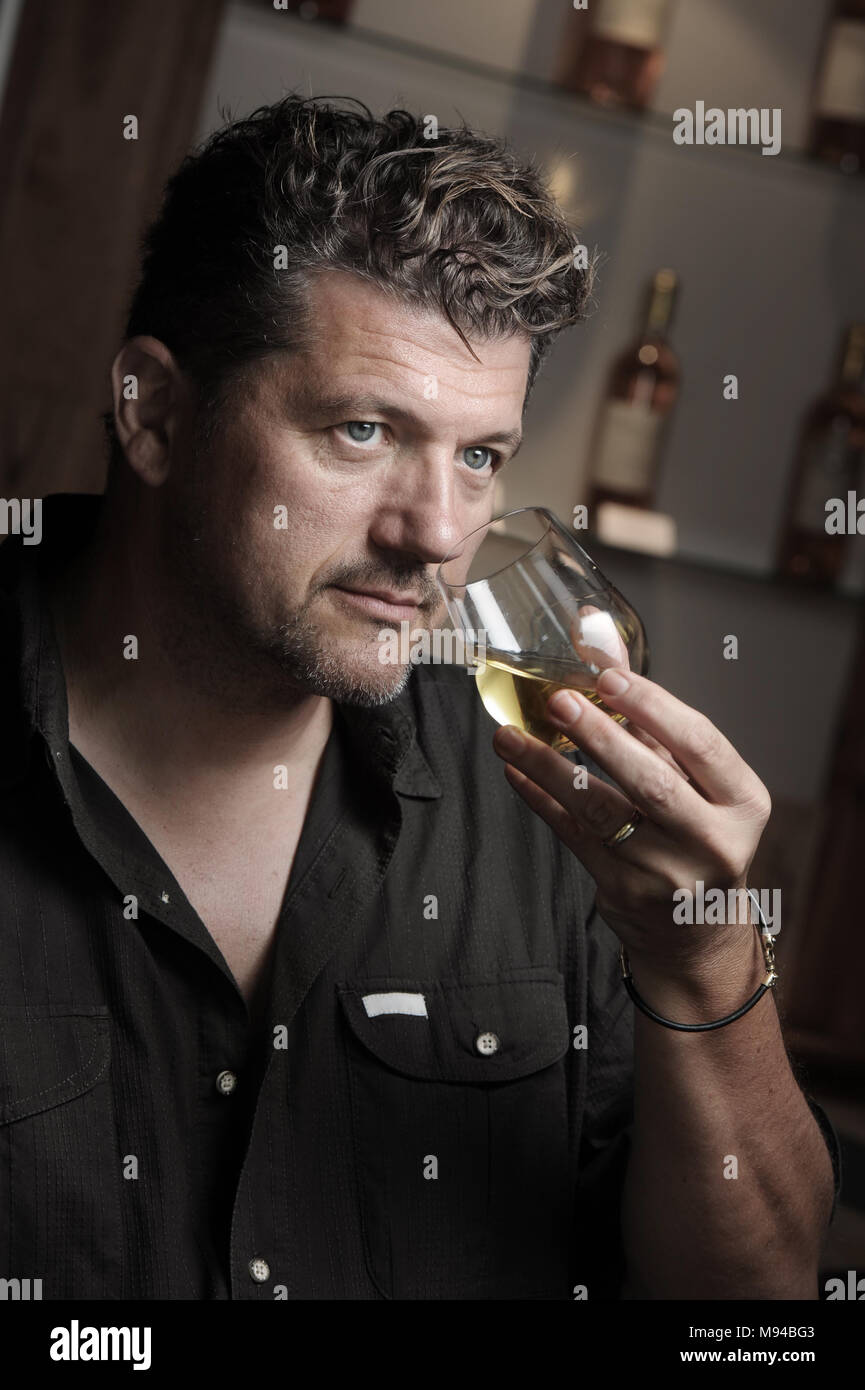 Winegrower in wine-cellar holding glass of wine, France Stock Photo