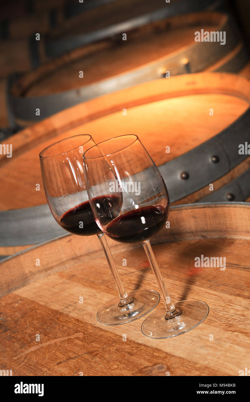 Two glass of red wine and old barrel in cellar, France Stock Photo