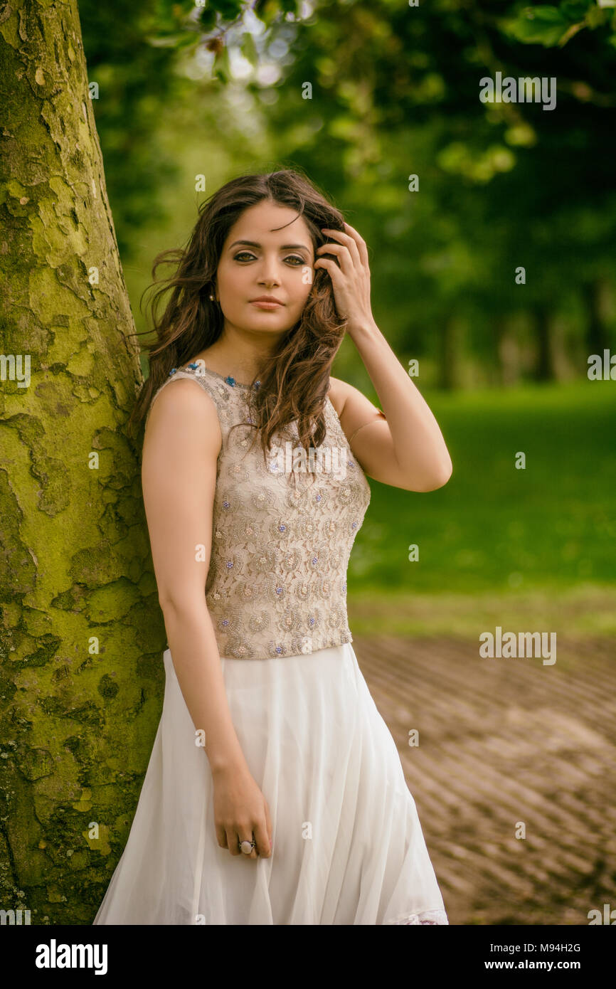 Beautiful young woman standing in the park Stock Photo - Alamy