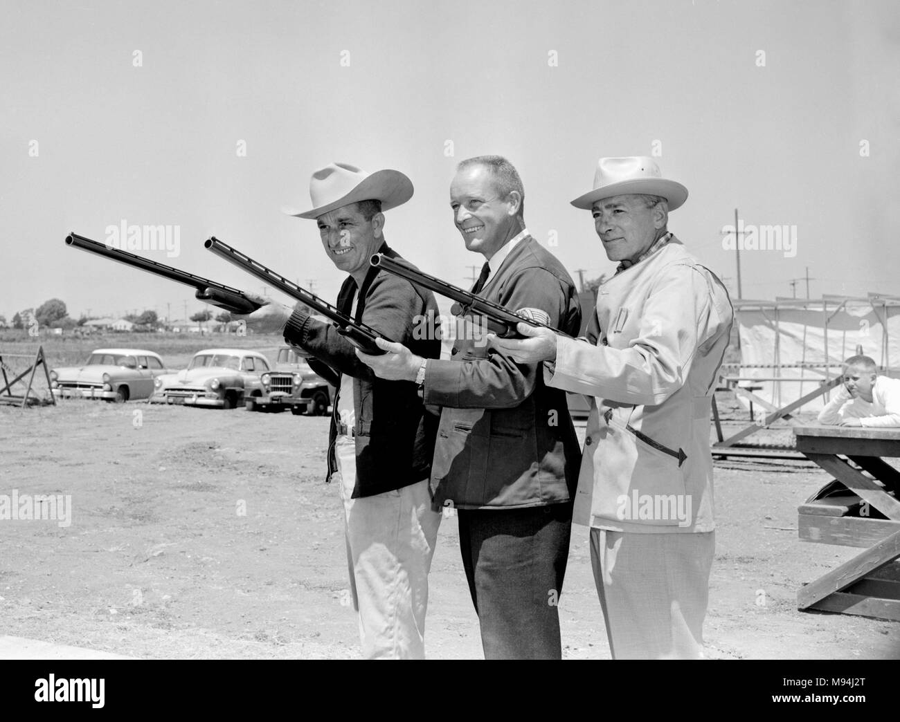Armed with smiles three men brandish shotguns at a California gun club, ca. 1962. Stock Photo