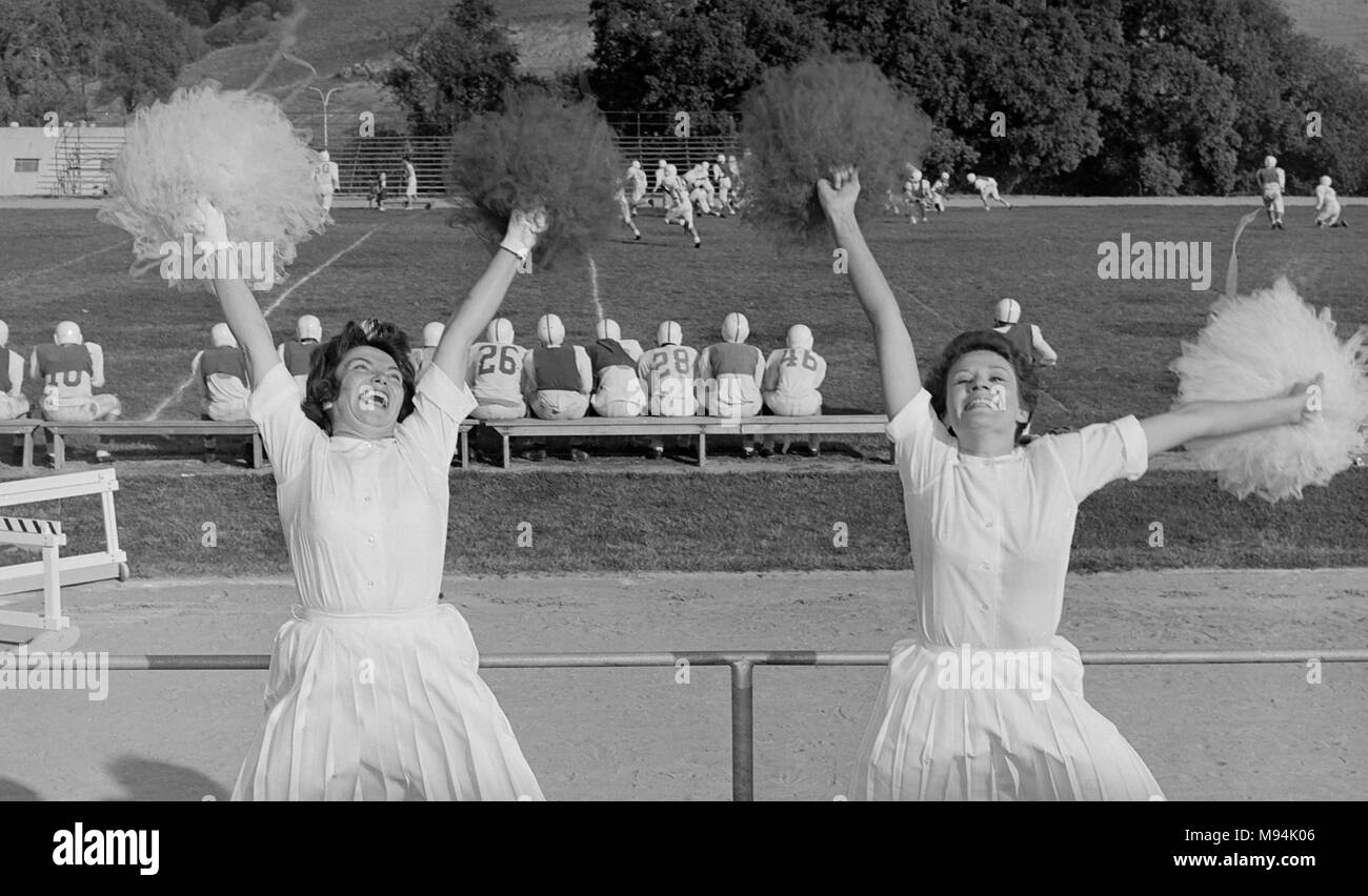 Two cheerleaders at a high school football are enthusiastic, ca. 1958. Stock Photo