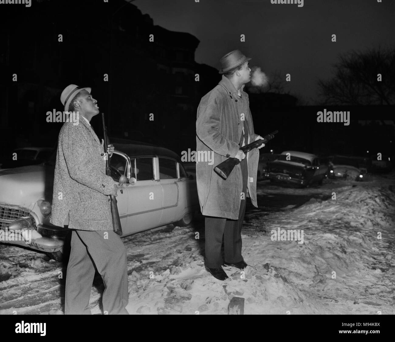 Shotgun-armed policemen search an area on Chicago’s West Side for murder suspect in 1962. Stock Photo