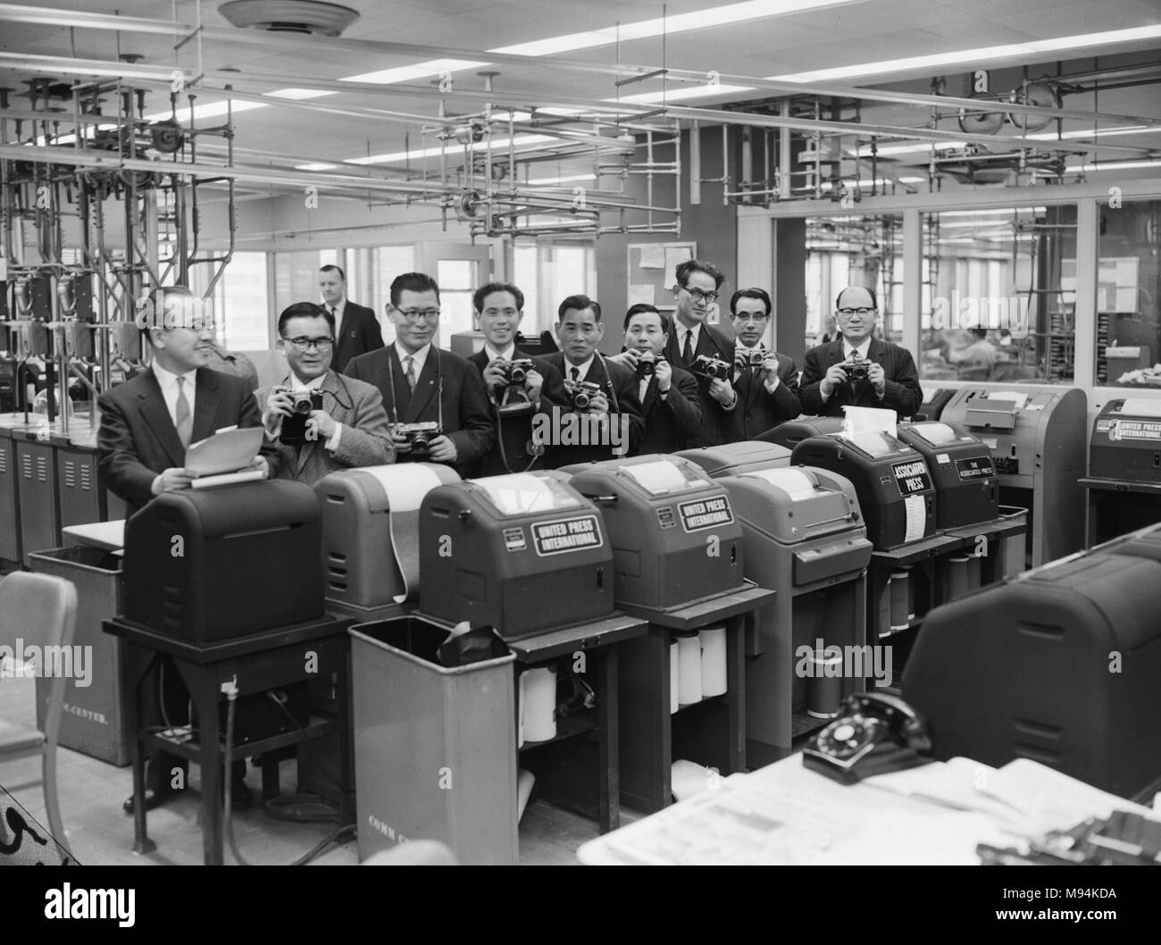 Japanese newspaper executives tour an American newspaper wire room in 1962. Stock Photo