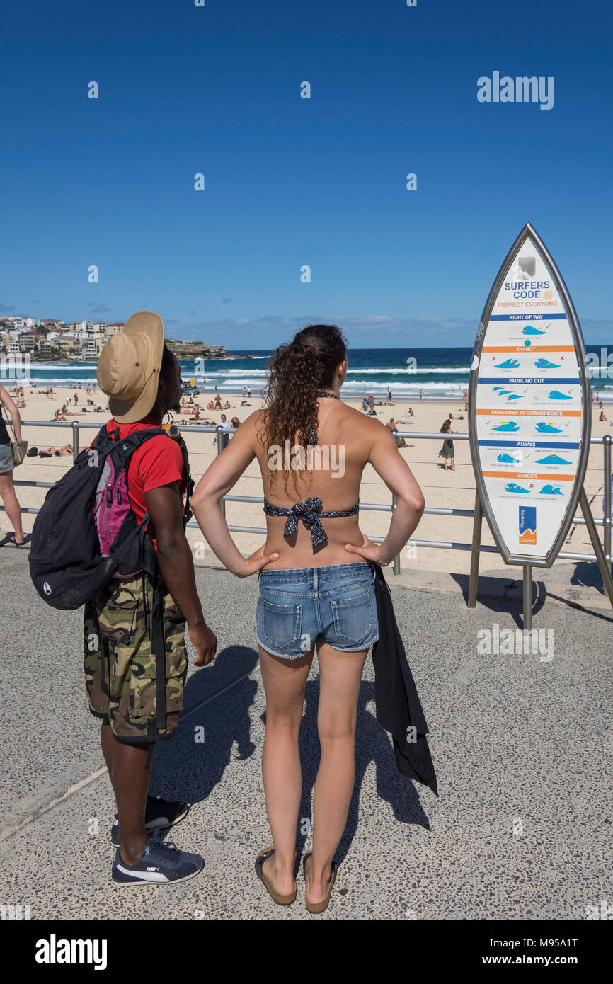 Couple on promenade reading surfer's code notice, Bondi Beach, Sydney, New South Wales, Australia Stock Photo
