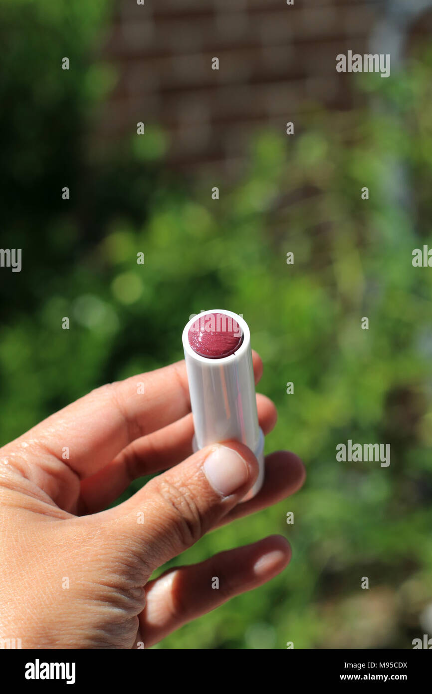 Close up of hand holding red colour lip gloss Stock Photo