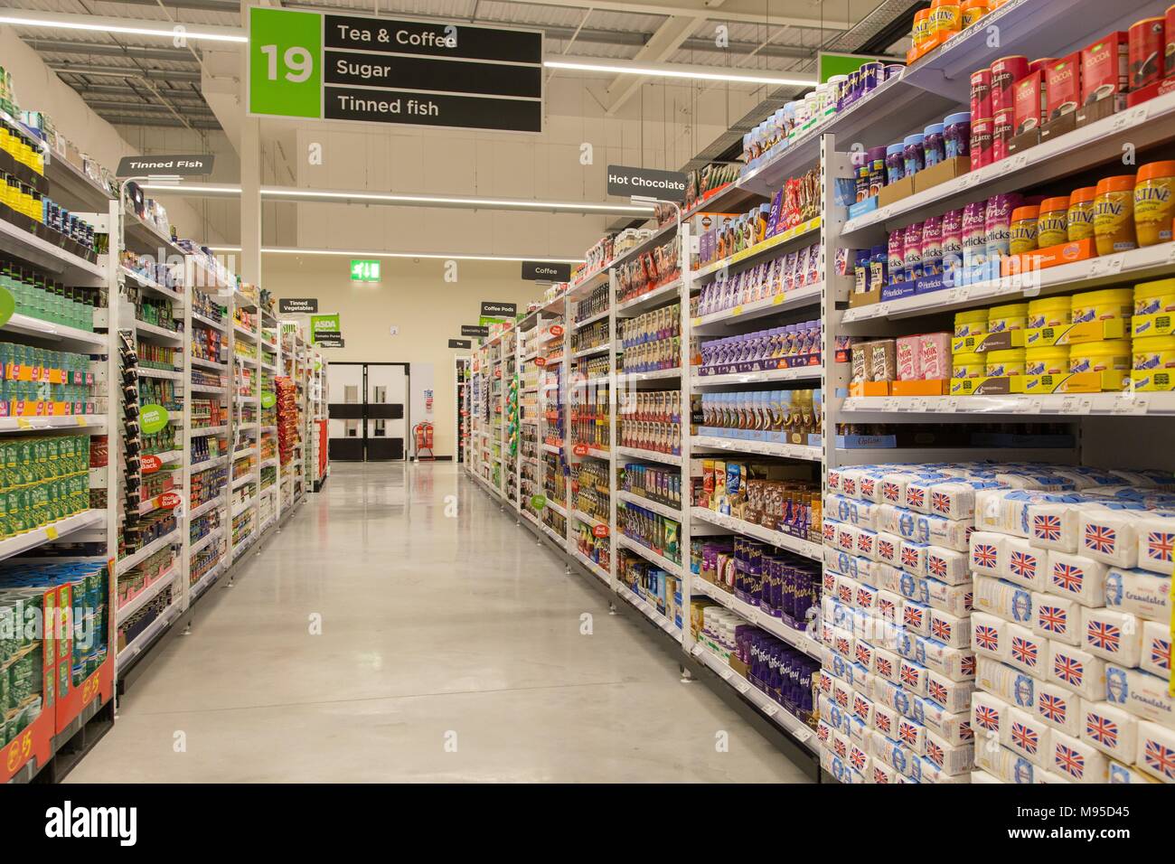 Tea and coffee, sugar,ovaltine,horlicks,tinned canned fish on full shelves in an Asda supermarket. Stock Photo